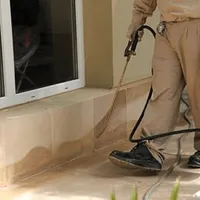 General pest control technician spraying exterior perimeter around a home in Chandler, AZ