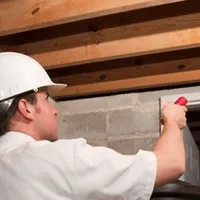 Termite inspection technician checking a basement wall and framing for termite activity in Chandler, AZ